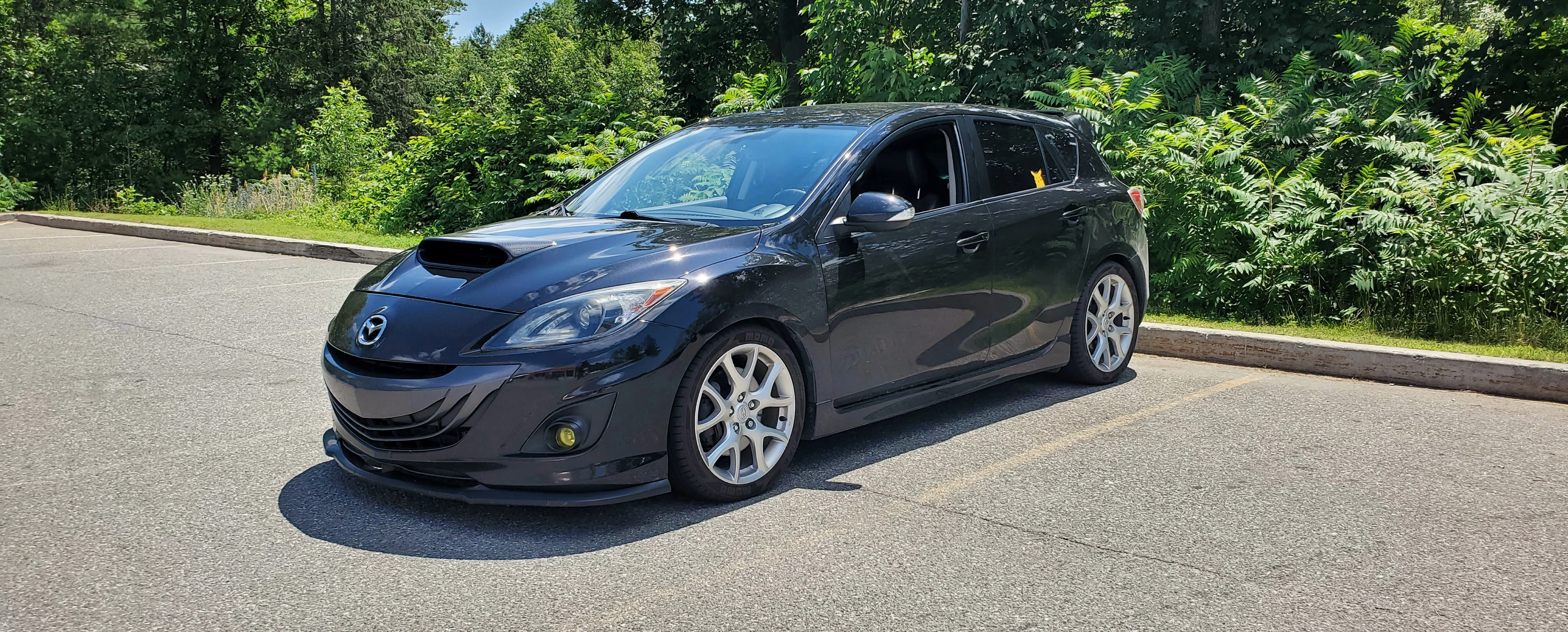 Mazdaspeed 3 dans un stationnement devant beaucoup de végétation.